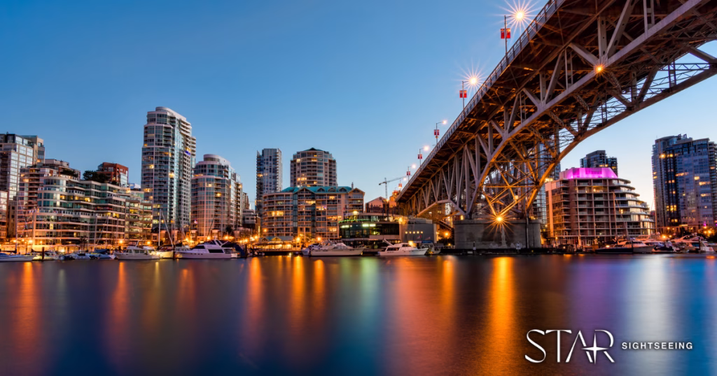 City skyline at dusk with high-rise buildings and a bridge over calm water, reflecting city lights; boats are docked along the shore.