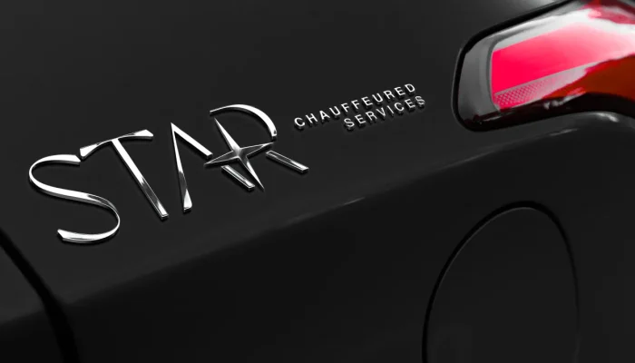 Close-up of a car with the words "STAR CHAUFFEURED SERVICES" in metallic letters next to a taillight and the fuel door.